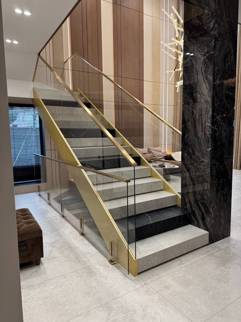 Staircase with a glass railing and gold-coloured metal elements in a private house