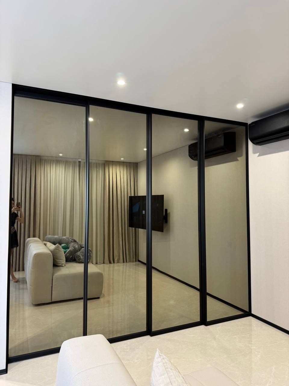 Sliding glass partition in tinted glass between a bedroom and a living room