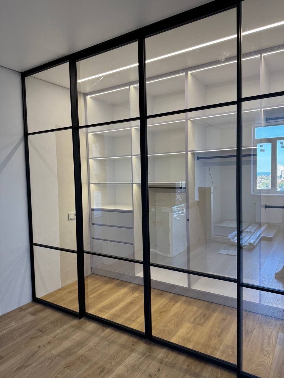 Light loft glass partition with clear glass in front of a wardrobe